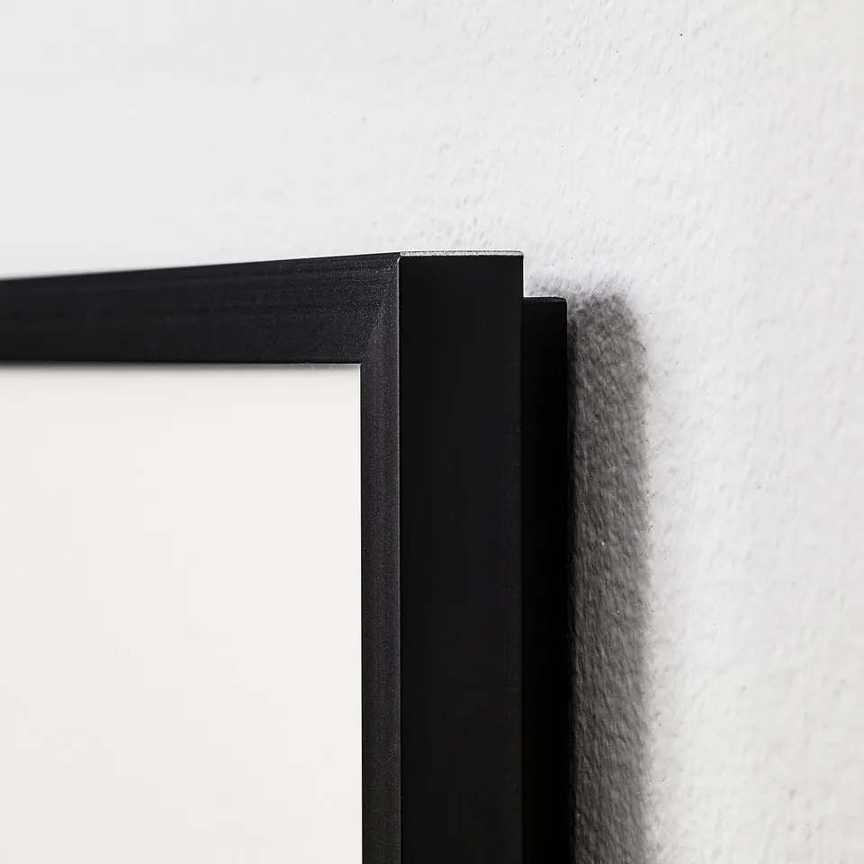 Black picture frame mounted on wall, showing sharp corners and smooth finish.
