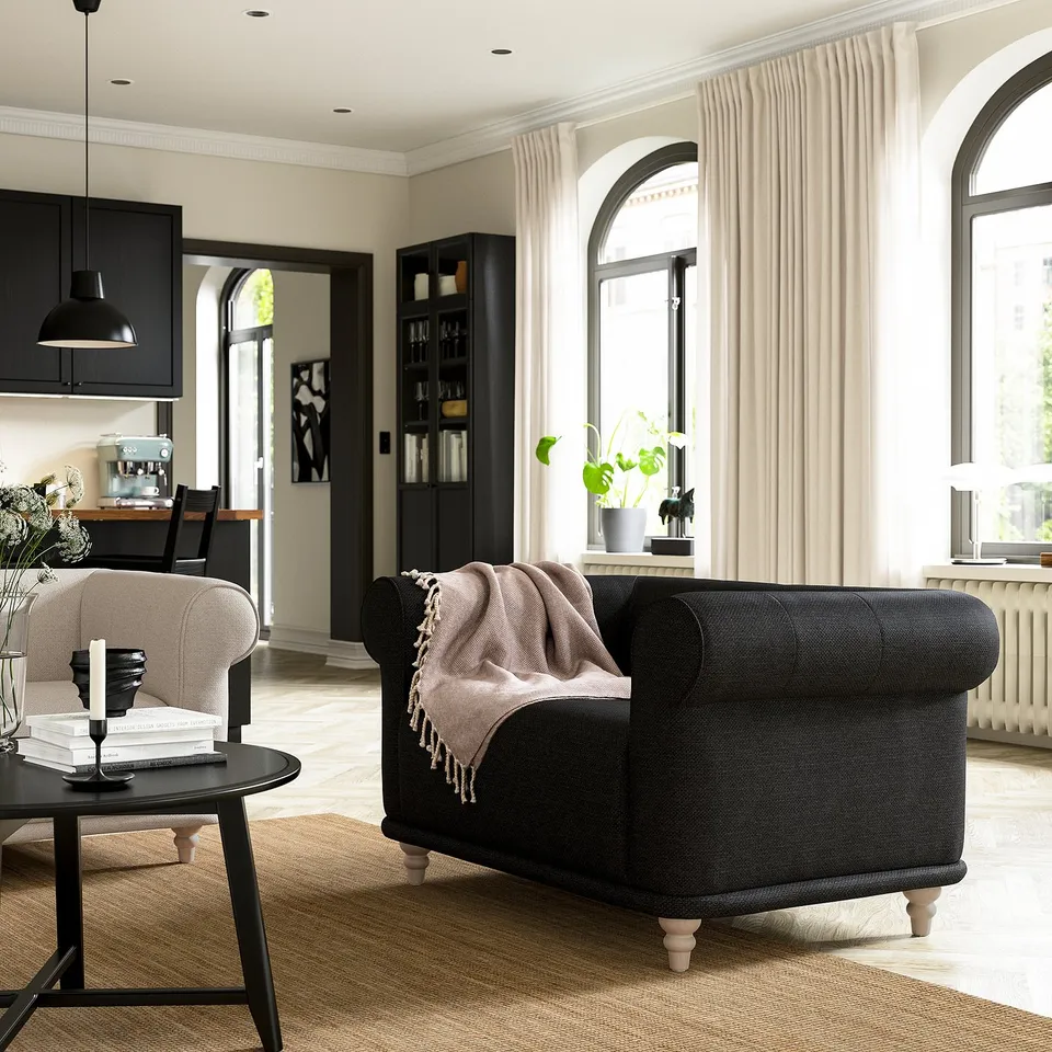 Cosy living room with black VISKAFORS armchair, white curtains, and arched windows. Modern minimalist decor with natural light.