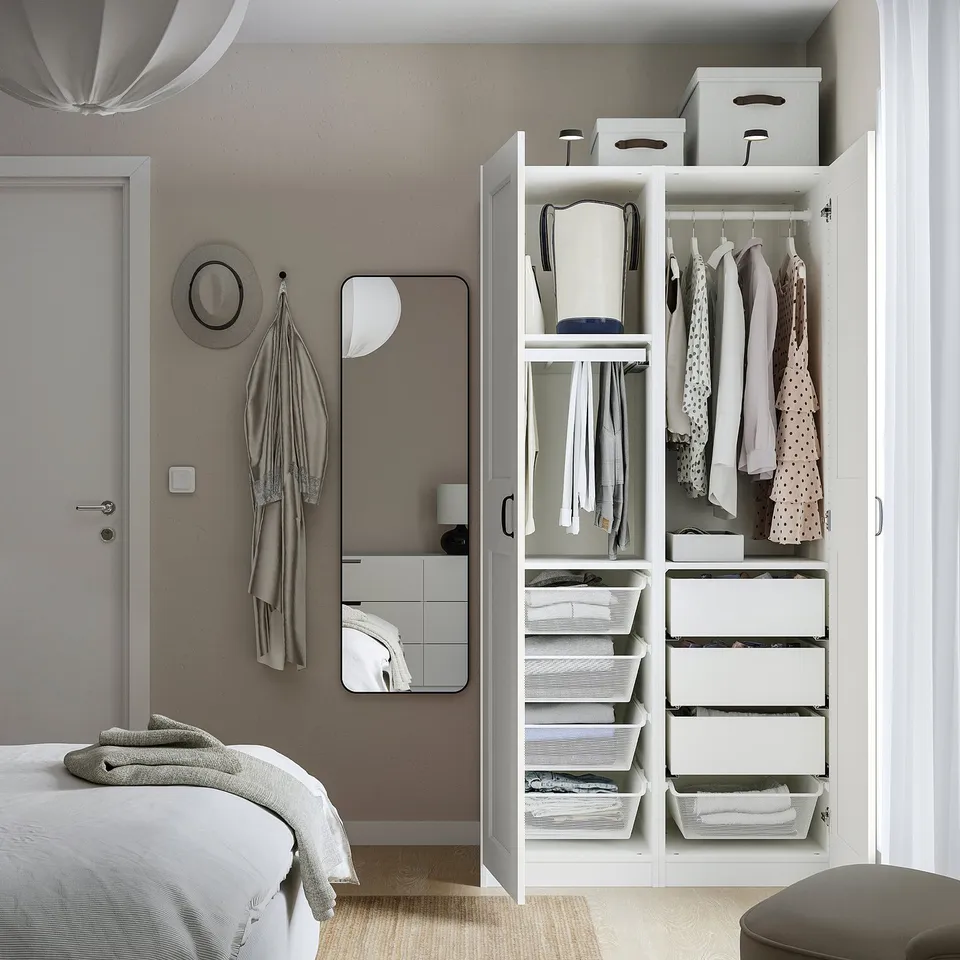 Neat bedroom with open wardrobe showing organised clothes, drawers, and mesh baskets. Hangers and boxes keep items tidy and visible.