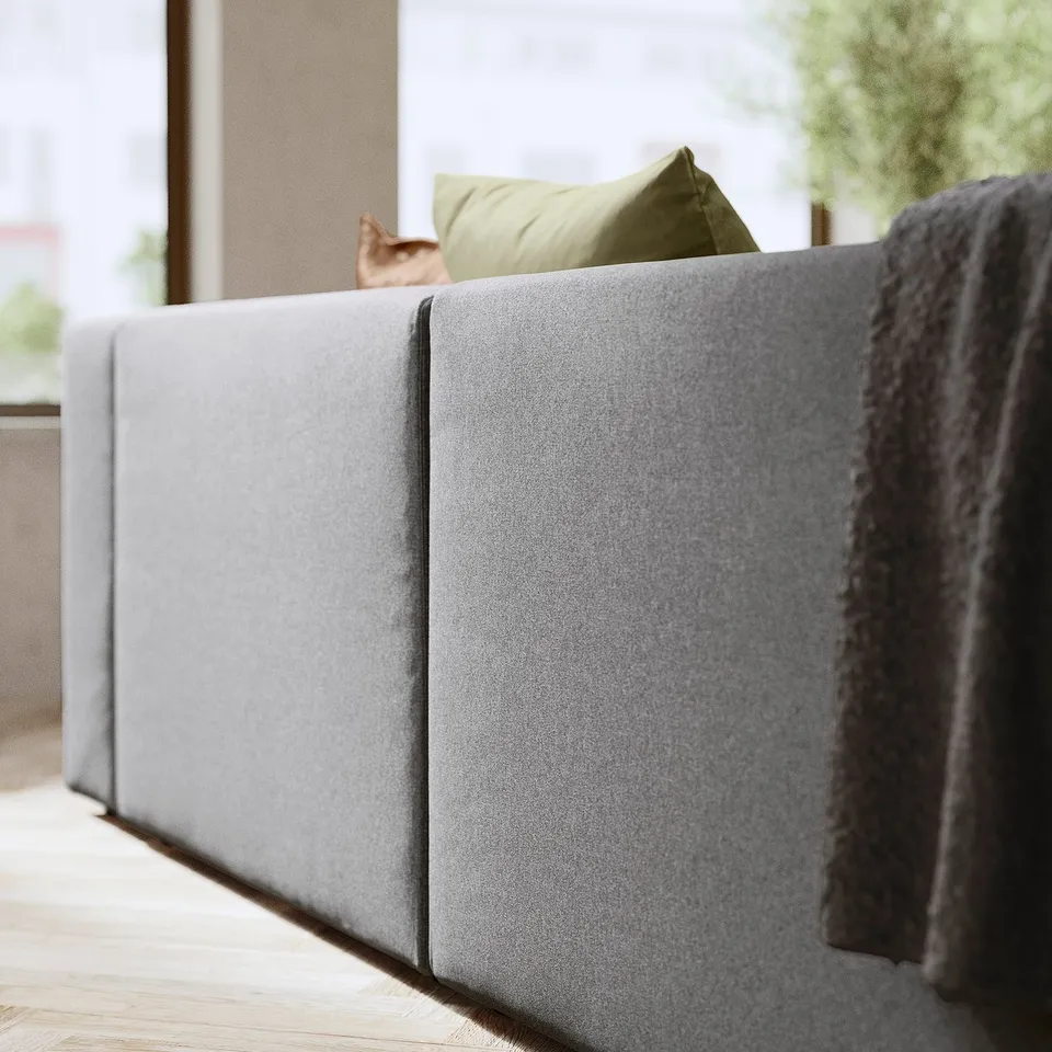 Modern grey JÄTTEBO sofa with olive pillow, cat, and soft blanket.