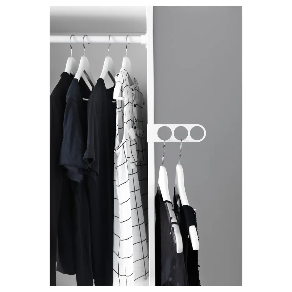KOMPLEMENT valet hanger in closet with white hangers for black and patterned clothes.