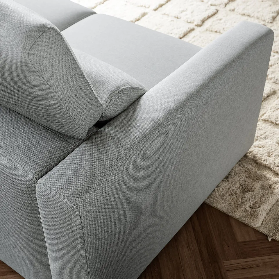 Sofa detail: light grey fabric, sturdy stitching, clean lines, comfortable cushions.