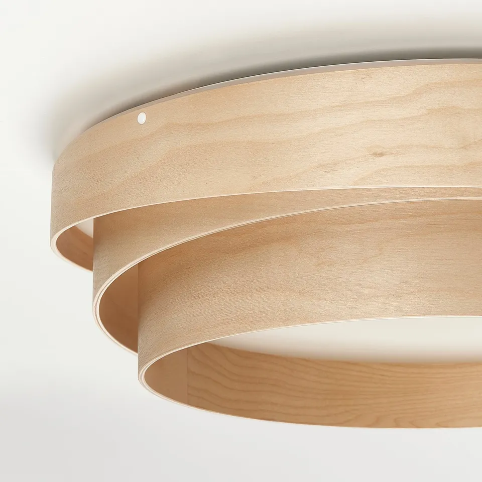 Modern circular wooden ceiling lamp with light diffusing through spaces between wood layers.