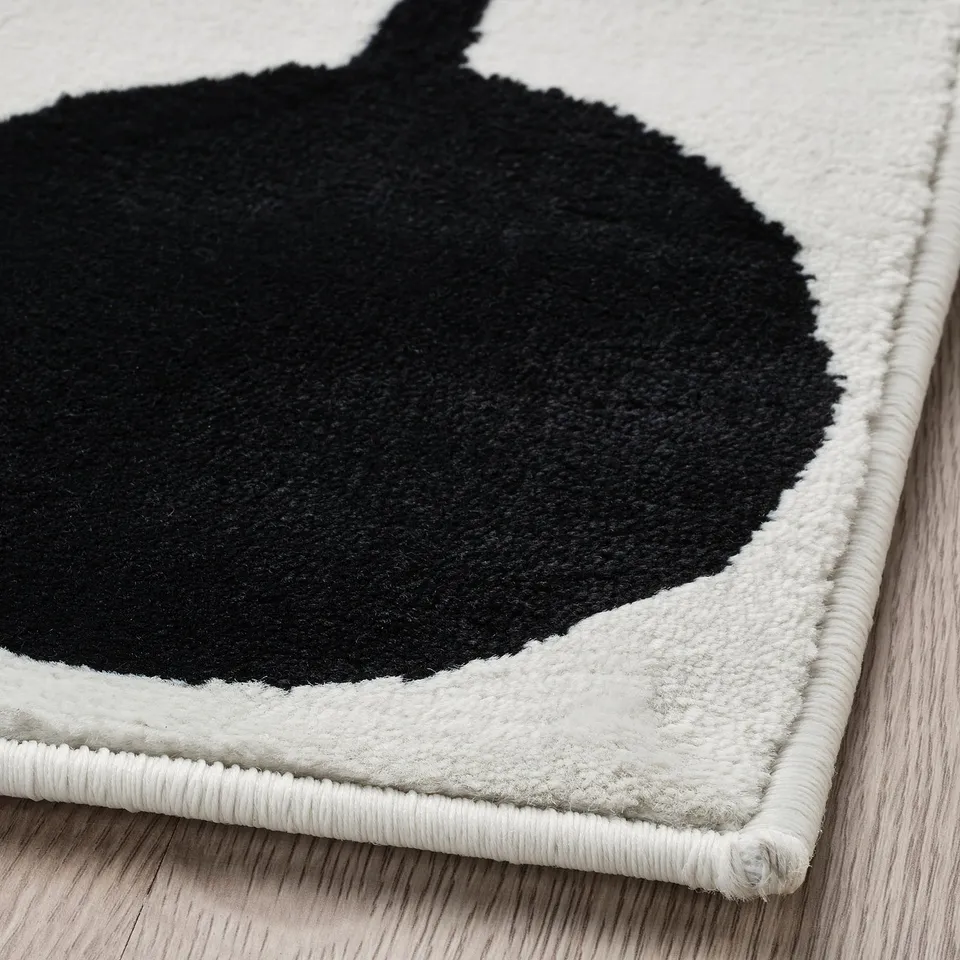 Black and white circular area rug with textured surface lying on wooden floor.