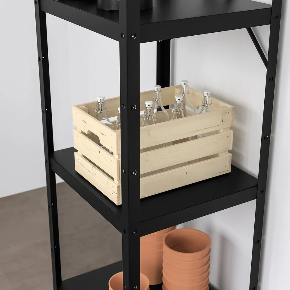 Black metal shelving unit with wooden crate holding white bottles and terracotta pots stacked below.