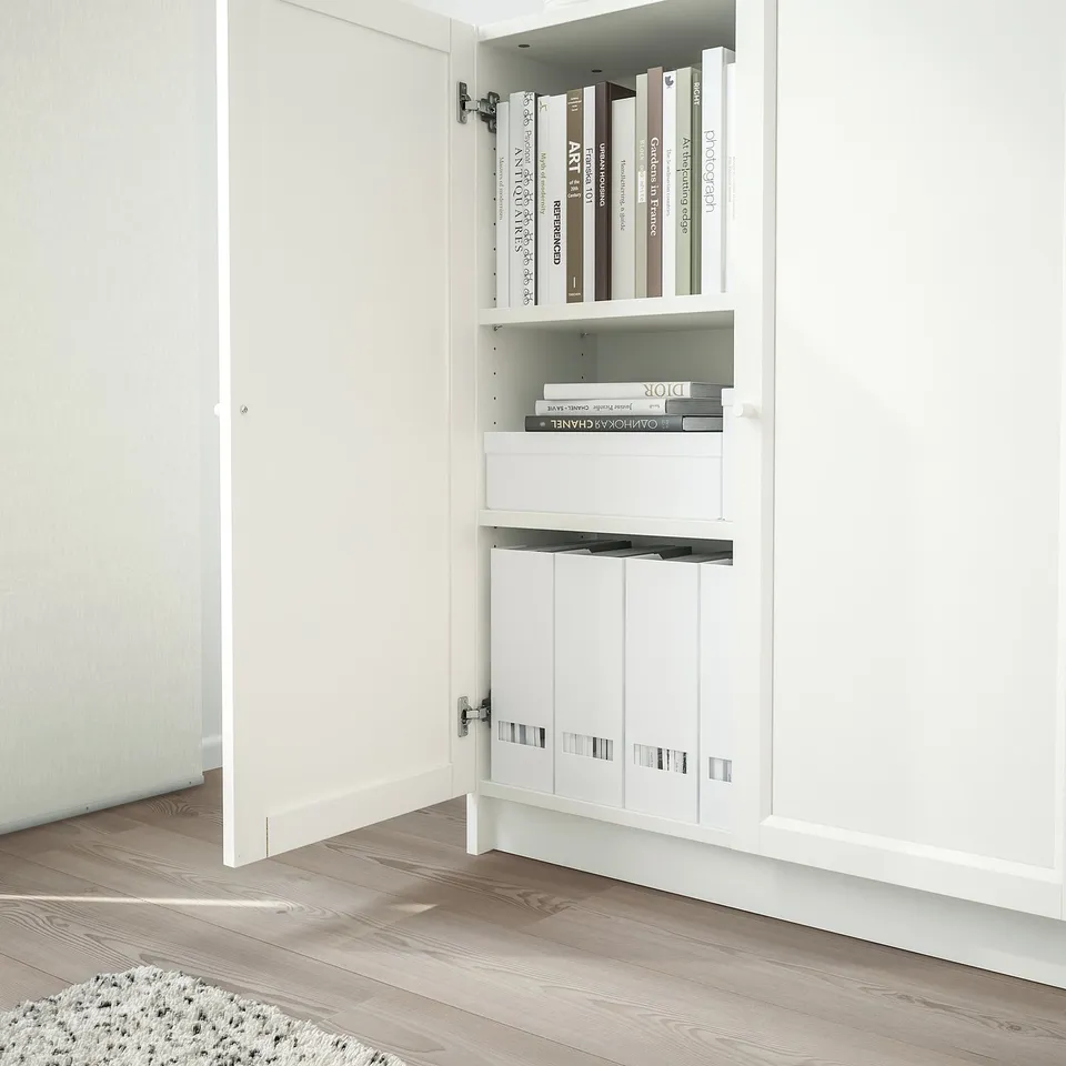 Open white BILLY bookcase with shallow shelves holding books, partially closed.