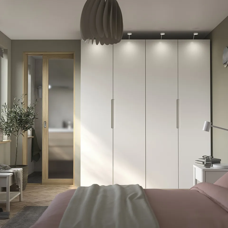 Modern bedroom with TONSTAD off-white wardrobe, wooden accessories, and pink bed linens.