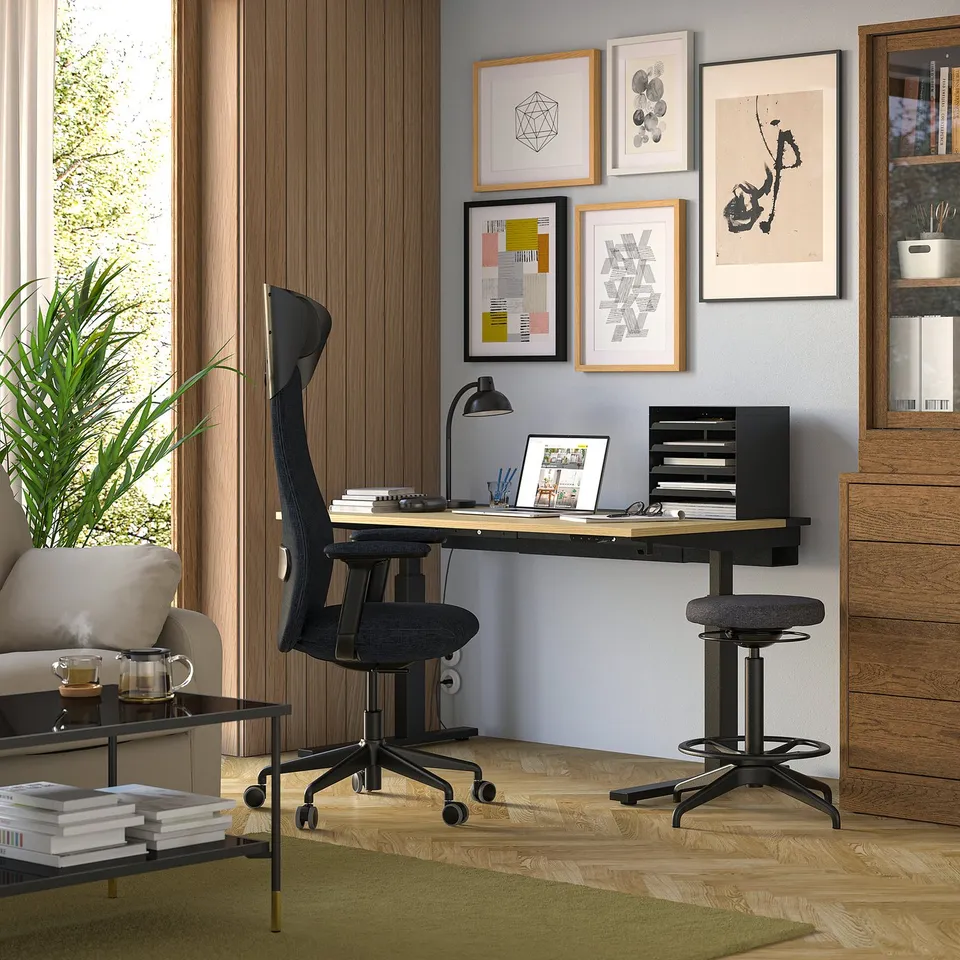 Home office with GRÖNFJÄLL black chair, wooden desk, art wall, green rug.
