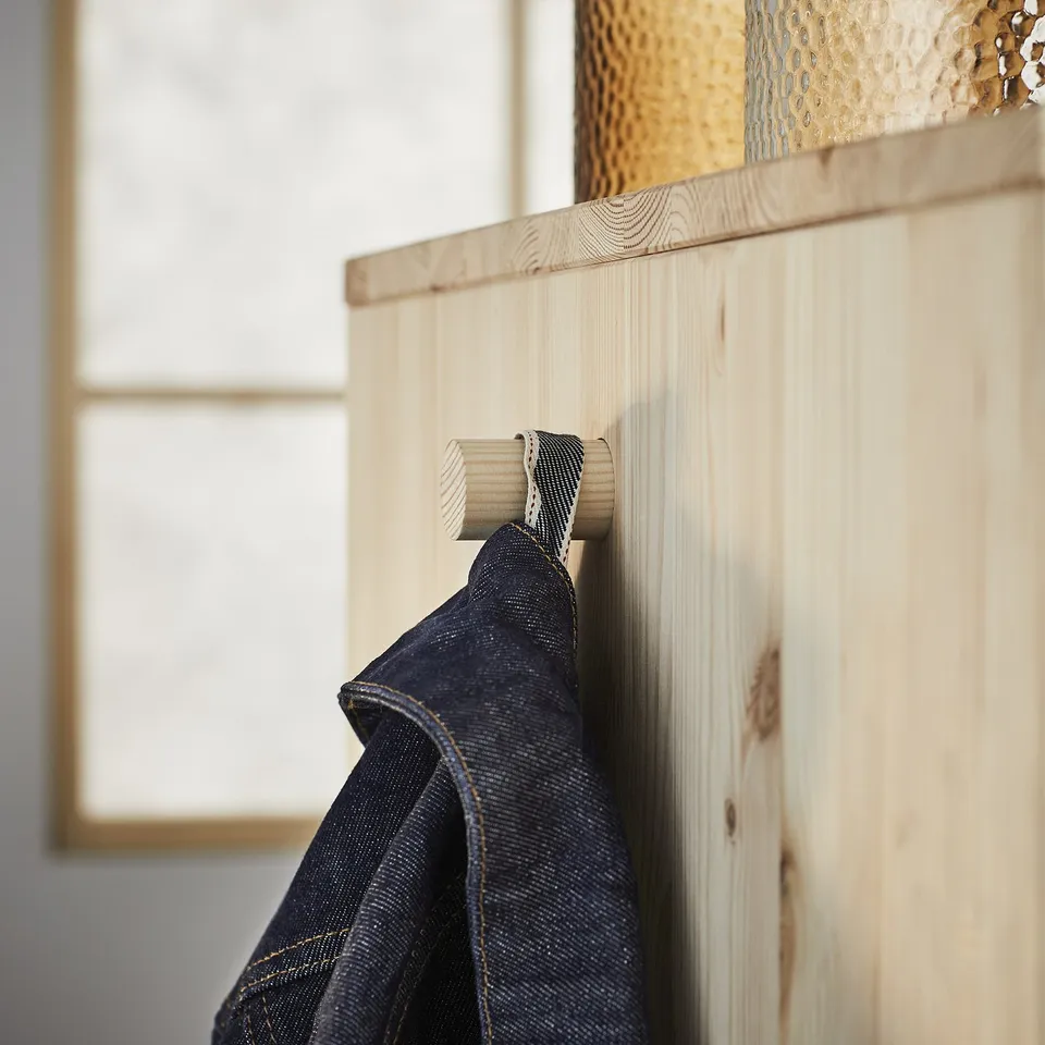 Wooden coat rack, light wood, hanging garment, denim jacket, natural finish, simple design.