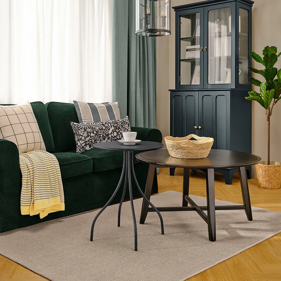 Modern living room with green sofa, dark side table near it, and blue glass cabinet.