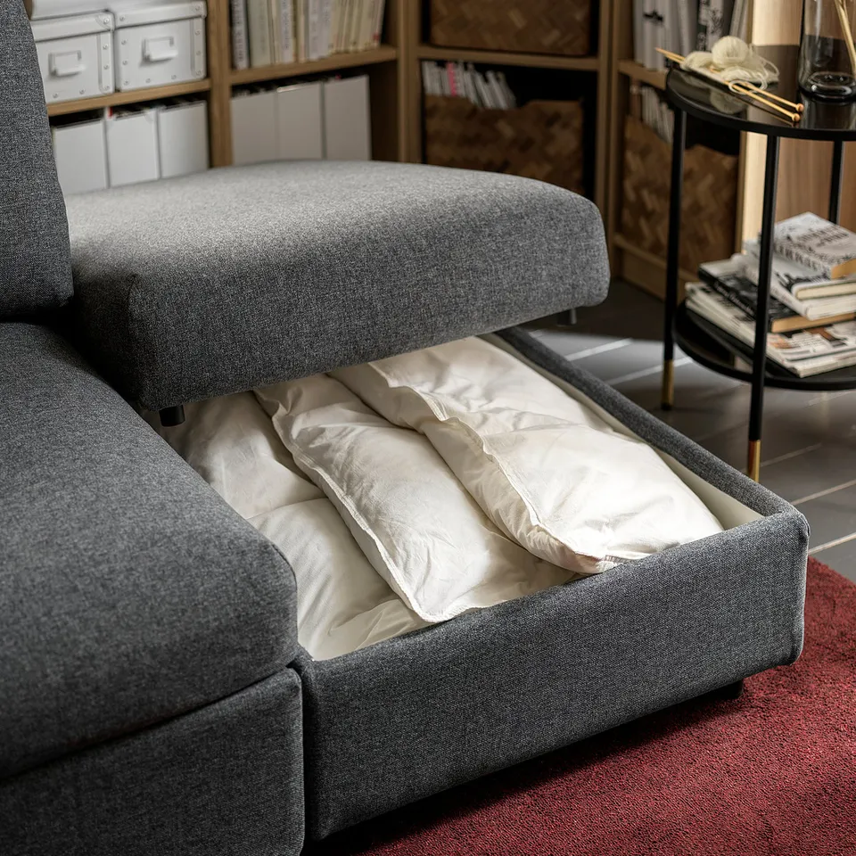 A grey VIMLE sofa with a pull-out bed. It has a sleek design and includes a storage compartment underneath the seat.