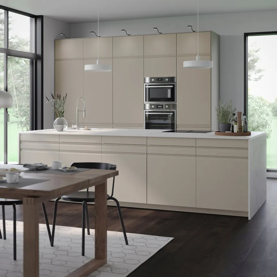 Modern kitchen with grey-beige METOD cabinets, wooden dining table, and large windows.