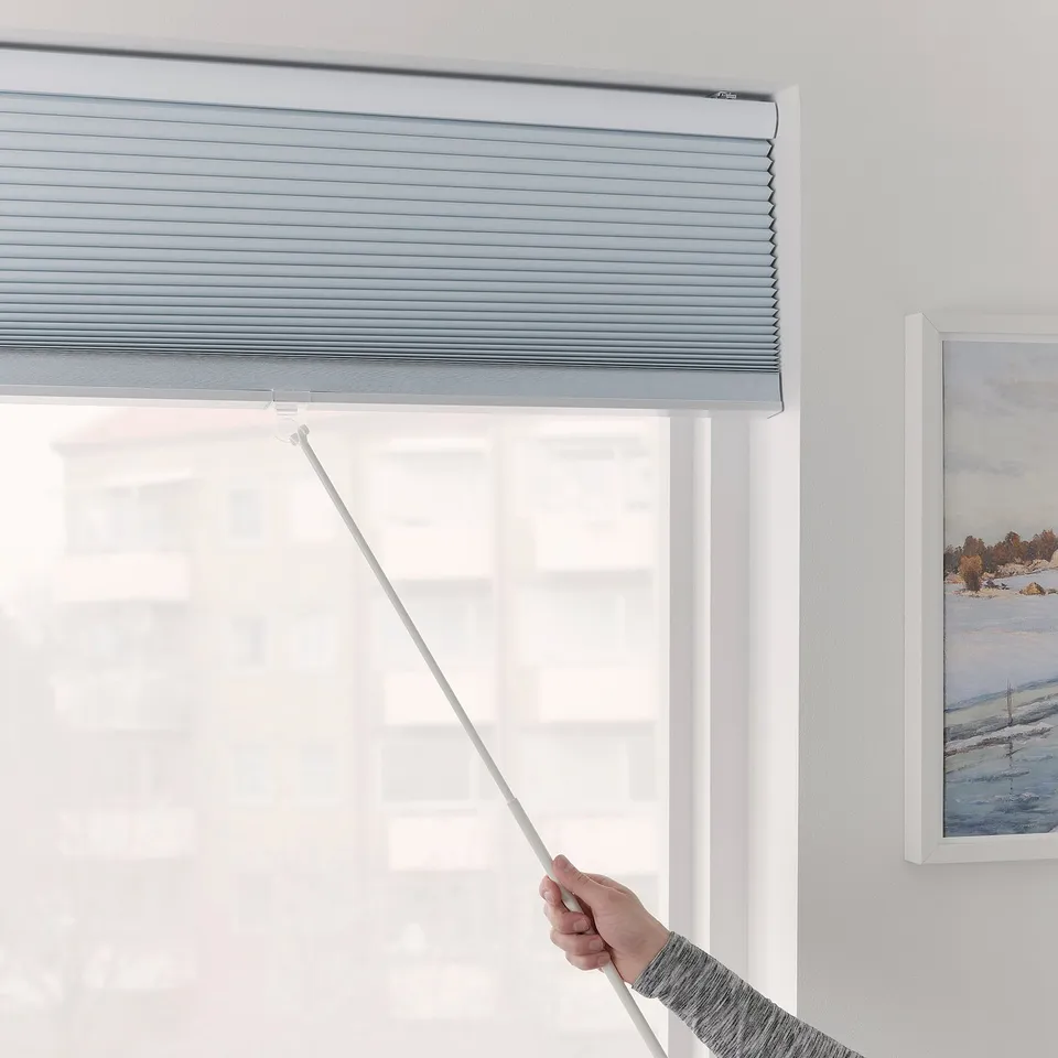 A hand pulls a TRIPPEVALS block-out blind with a draw rod for easy use, ensuring light control and safety.