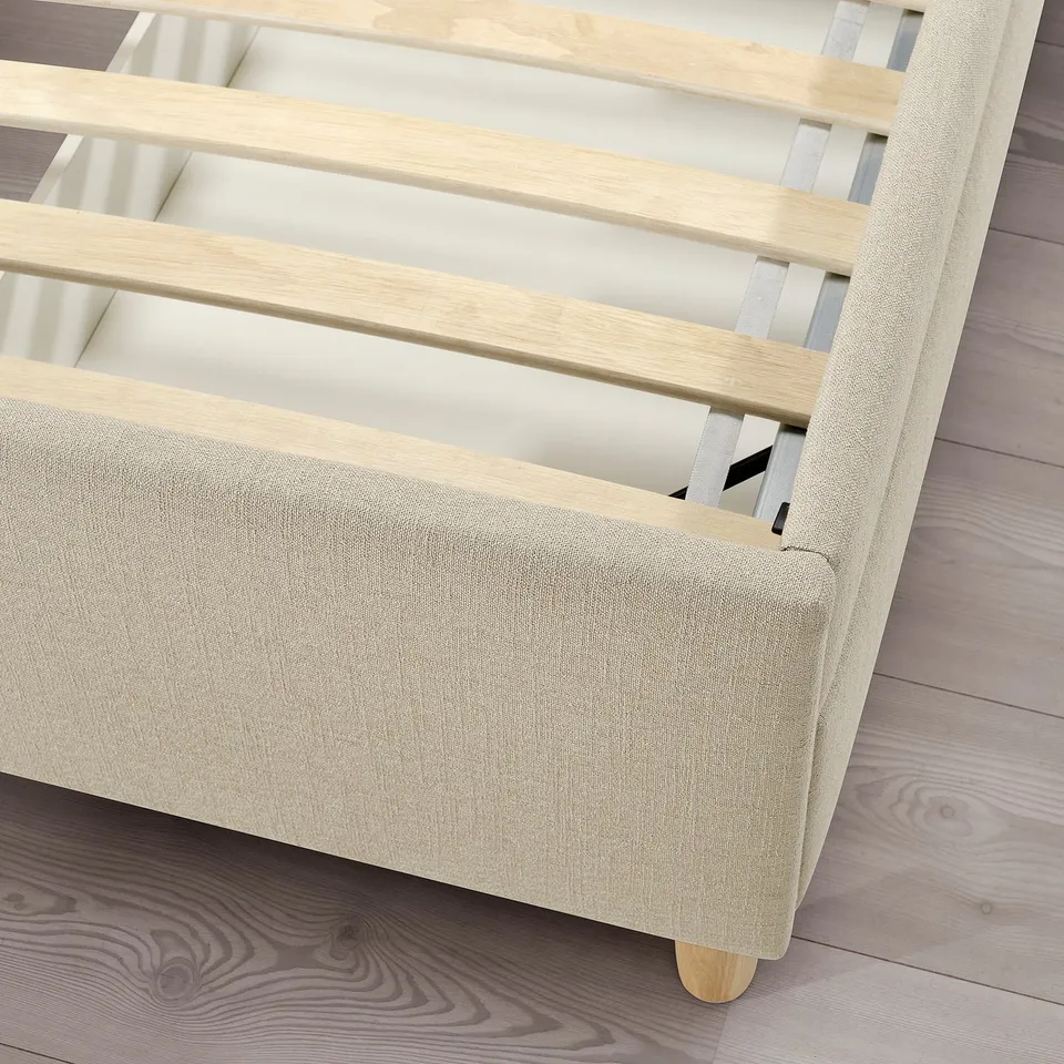 Modern bed with beige upholstery and wooden slats. Soft-closing drawers and sturdy wooden legs.