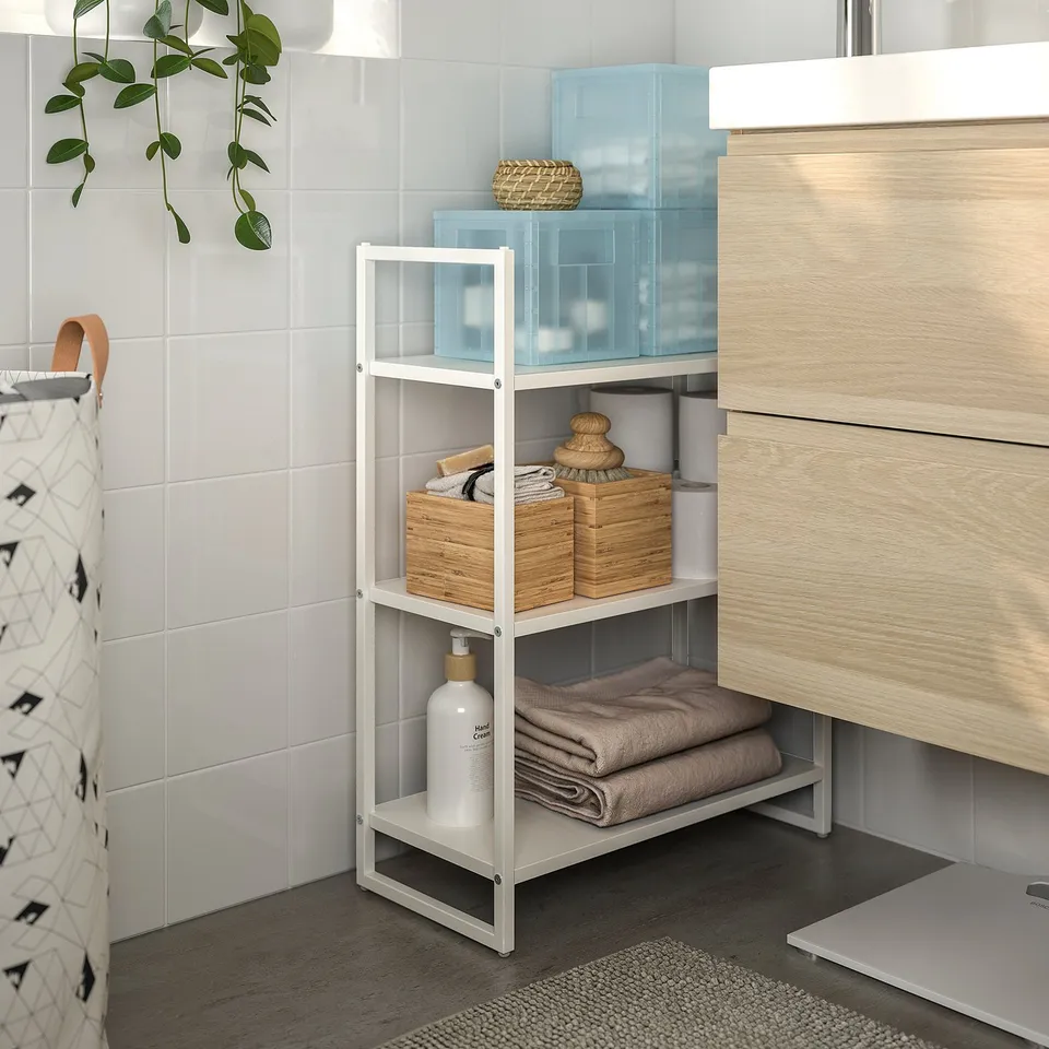 Bathroom with tiled wall, metal shelf with baskets and towels, wooden vanity, hanging plant.