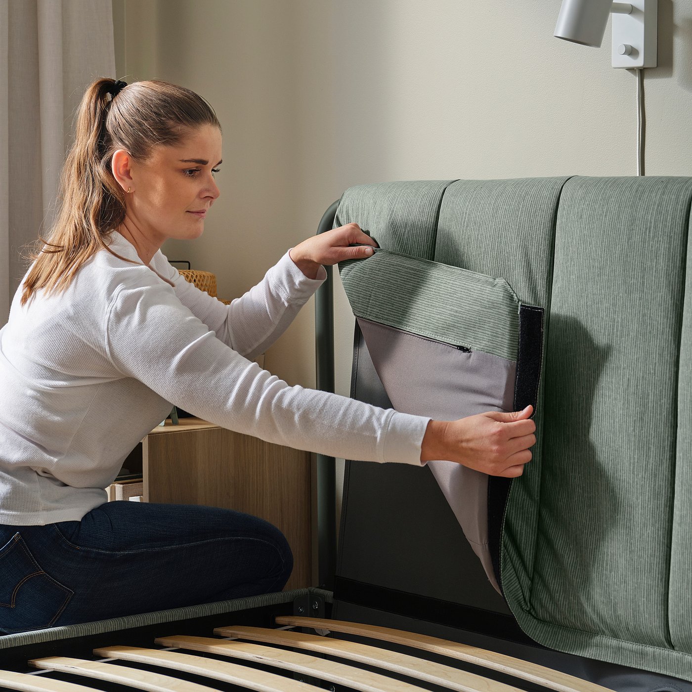 A person is adjusting the bed frame, showing its adjustable feature.