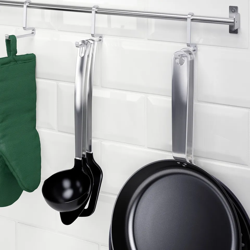 Wall storage hooks hang kitchen utensils and a frying pan, maximising space.
