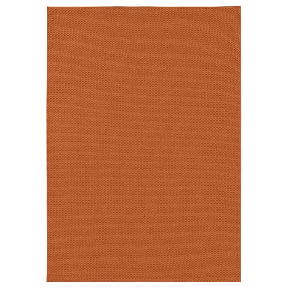 A rectangular, orange MORUM rug. Its texture is flat-woven, suitable for both indoor and outdoor use in moderate climates.