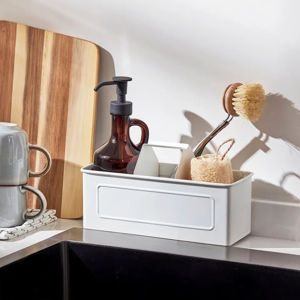 White countertop organiser with soap dispenser, dish brush, and sponge.