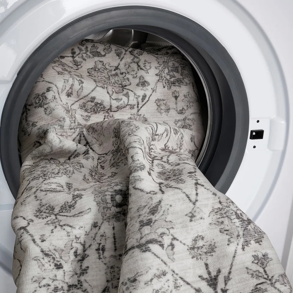 Washing machine drum with floral-patterned textile inside.