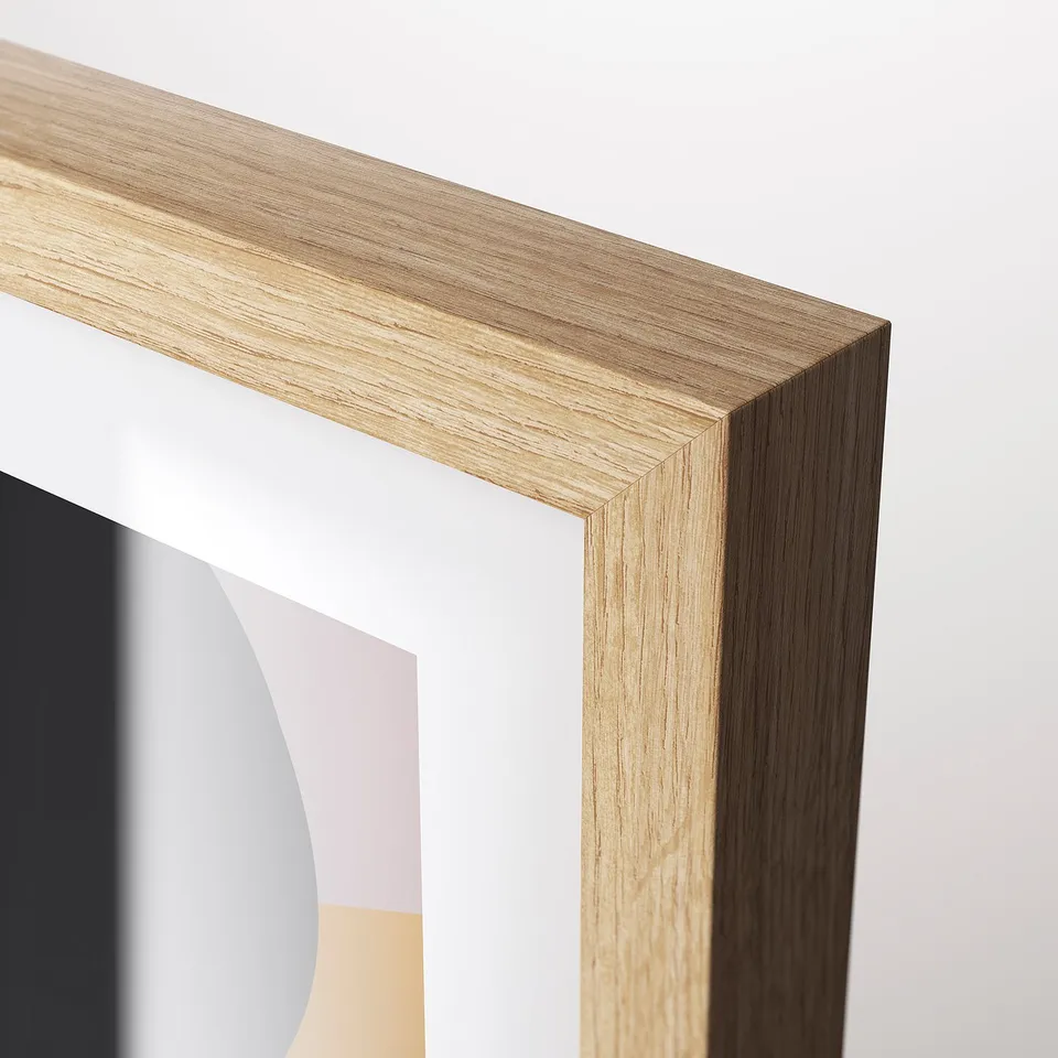 Light wooden picture frame, well-crafted with detailed grain, holding colourful, abstract artwork, displayed against clean white background.