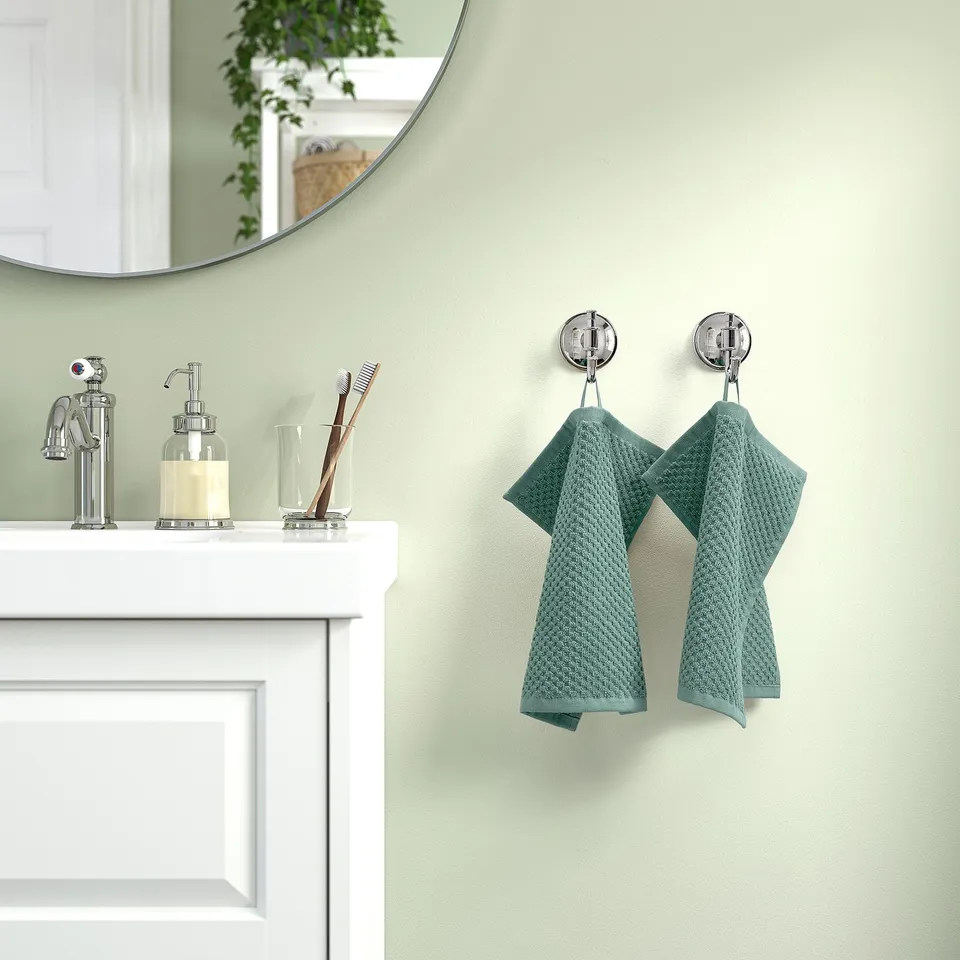 Bathroom with green wall, white sink, chrome fixtures, & GULVIAL towels.