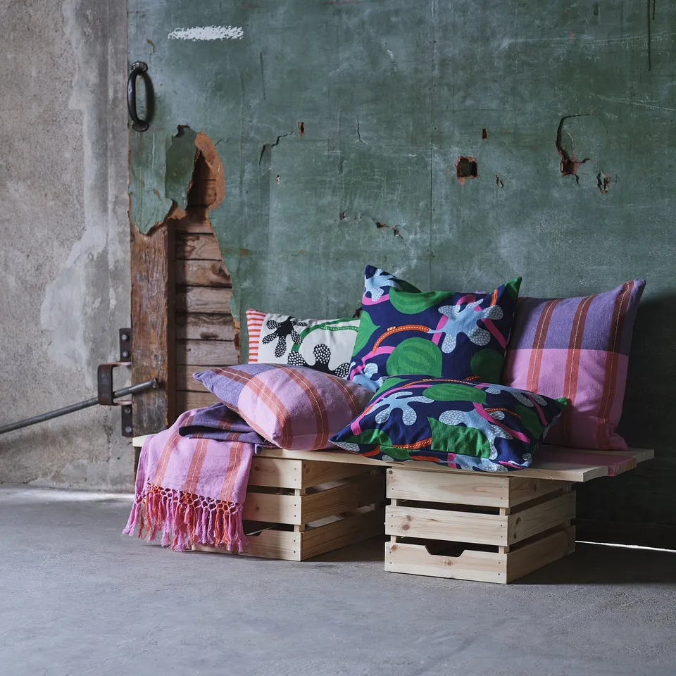 Cosy, colourful pillows on wooden crates; bright patterns, soft texture.