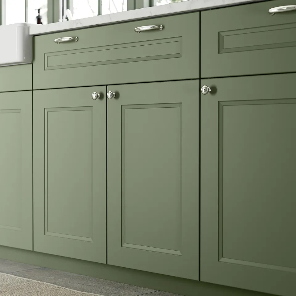Green kitchen cabinets with stylish chrome knobs and handles.