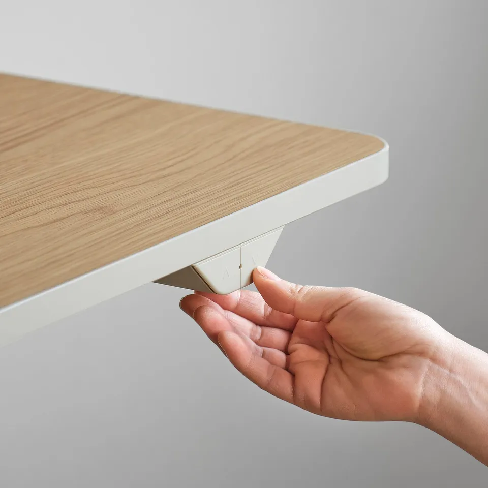 Person adjusting white and wood desk height.