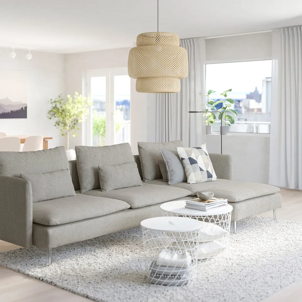 Modern minimalist living room: grey SÖDERHAMN sofa, white coffee table, large window, hanging light, plants.