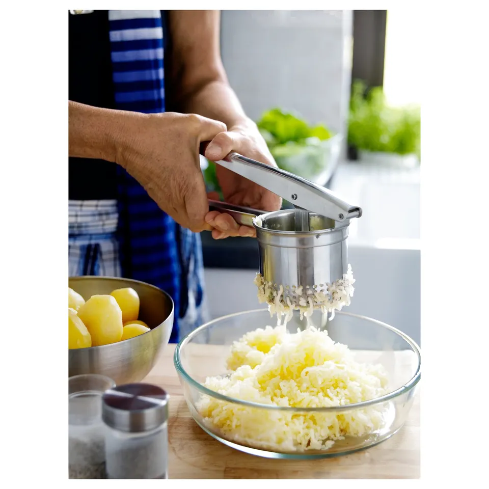 A person grates a lemon using a stainless steel grater into a glass bowl.
