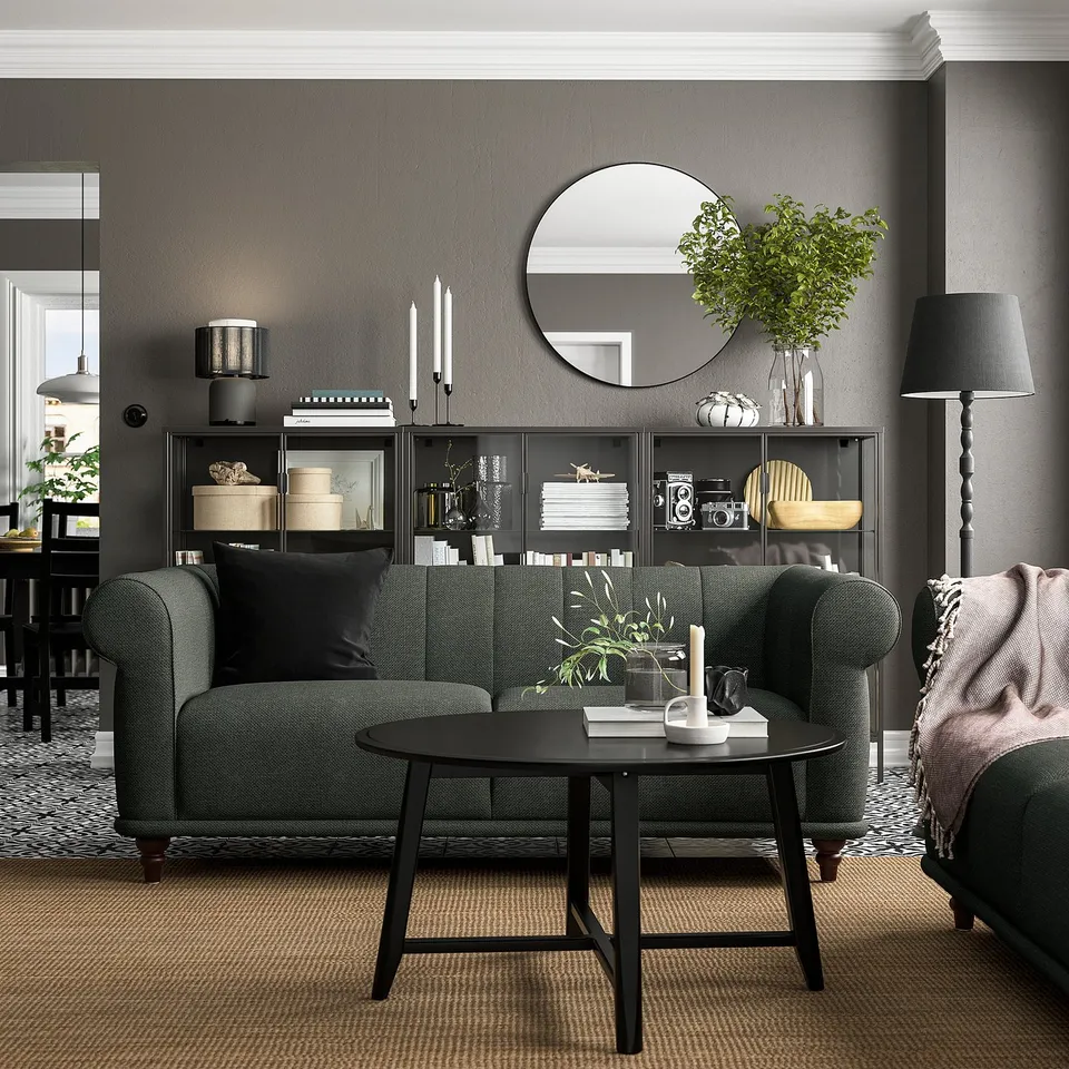 Modern living room with VISKAFORS green sofa, black coffee table, grey walls, round mirror, and black floor lamp.