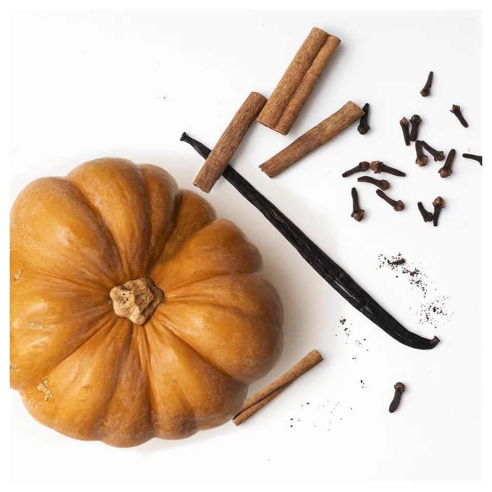 Small pumpkin-shaped white candle with cinnamon, vanilla, cloves; autumn spices.