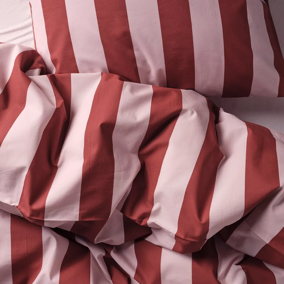 Crisp striped bed linens in red and white, showcasing high-quality, tightly woven percale fabric.
