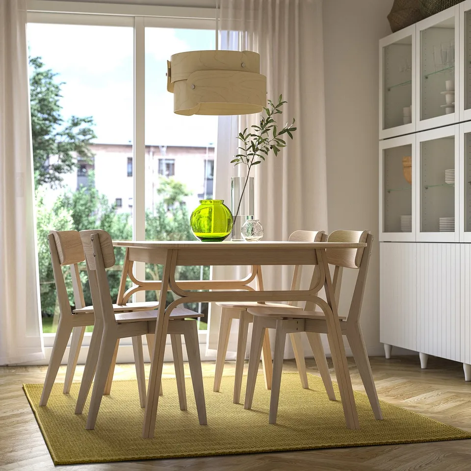 Modern dining room with light wood table, green rug, large window, pendant lamp, cabinet, and vase. Calm ambiance with MORUM rug.