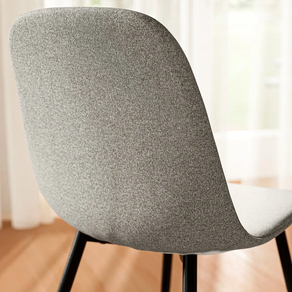 Modern upholstered chair with grey fabric, curved back, and black metal legs.