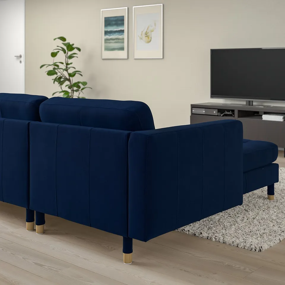Modern navy velvet sofa with chaise, cosy living room, abstract art, potted plant.