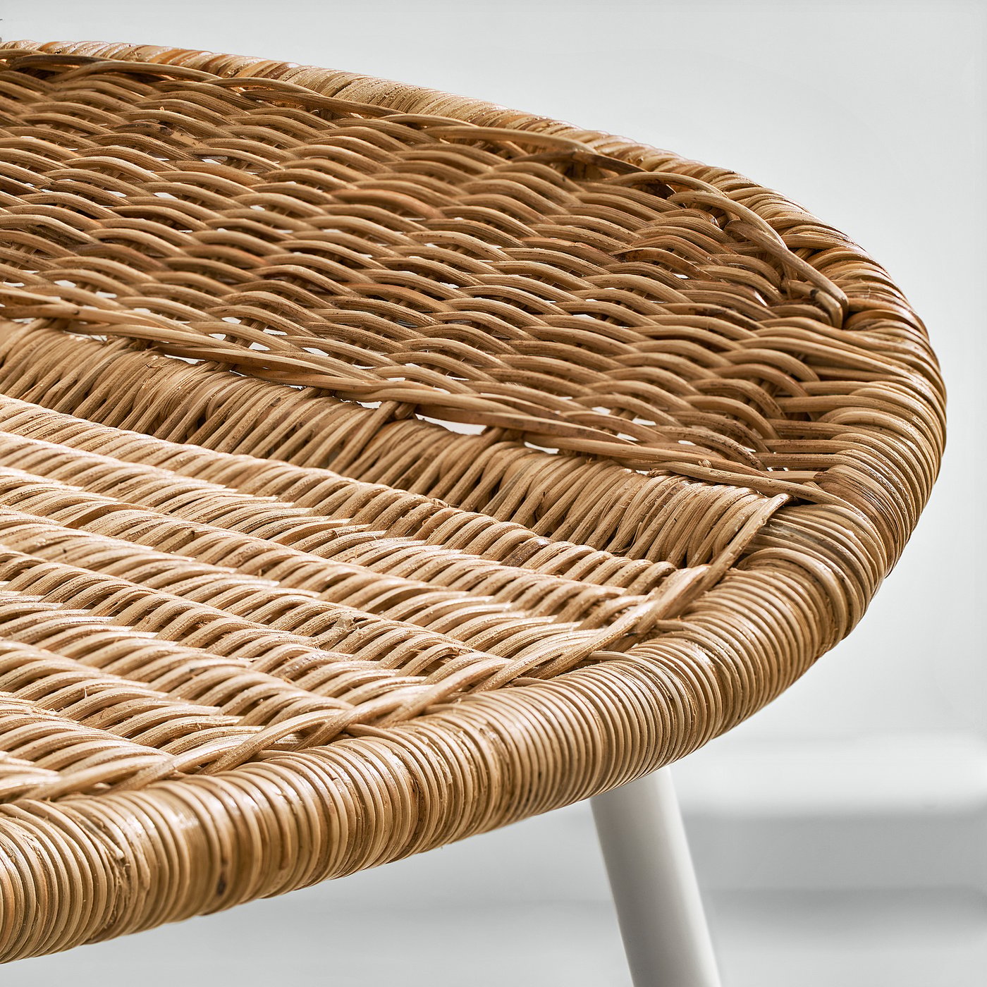 Woven rattan chair close-up, showcasing intricate, handcrafted texture. Light brown wicker pattern, natural material quality evident.