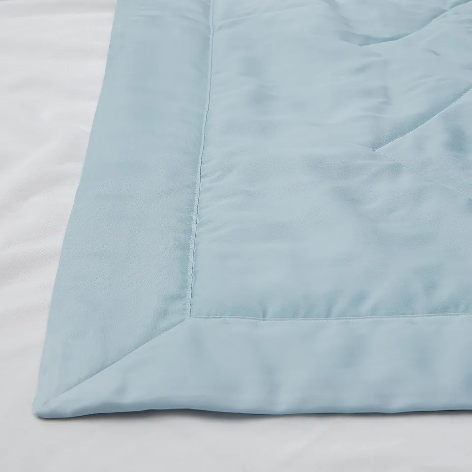 Light blue bedding with smooth texture and subtle pattern, laid neatly on bed.