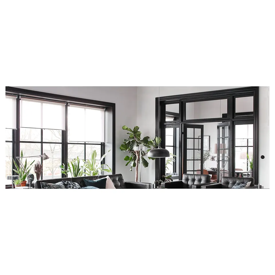 Modern living space with large windows, plants, and sleek furniture. Black framed windows and dark decor.