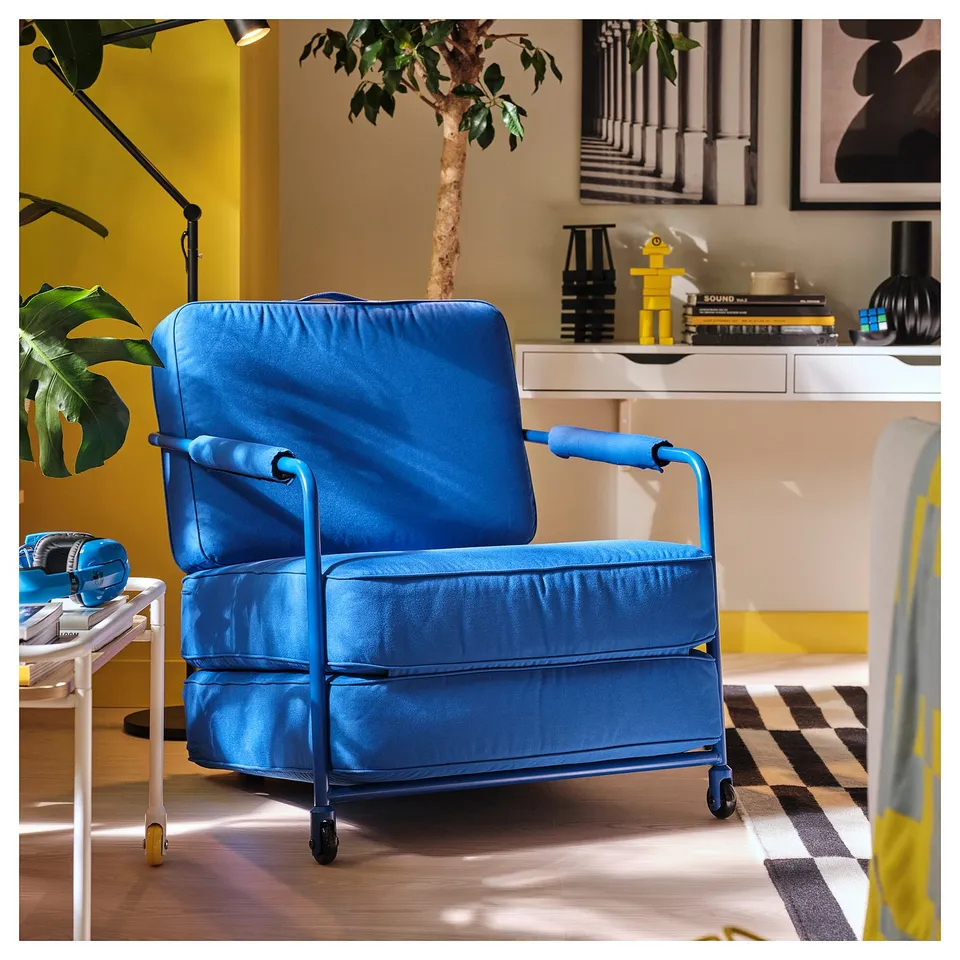 BRÄNNBOLL blue gaming chair with fold-out seat, sturdy steel frame, in modern room with yellow accents, beside small table.