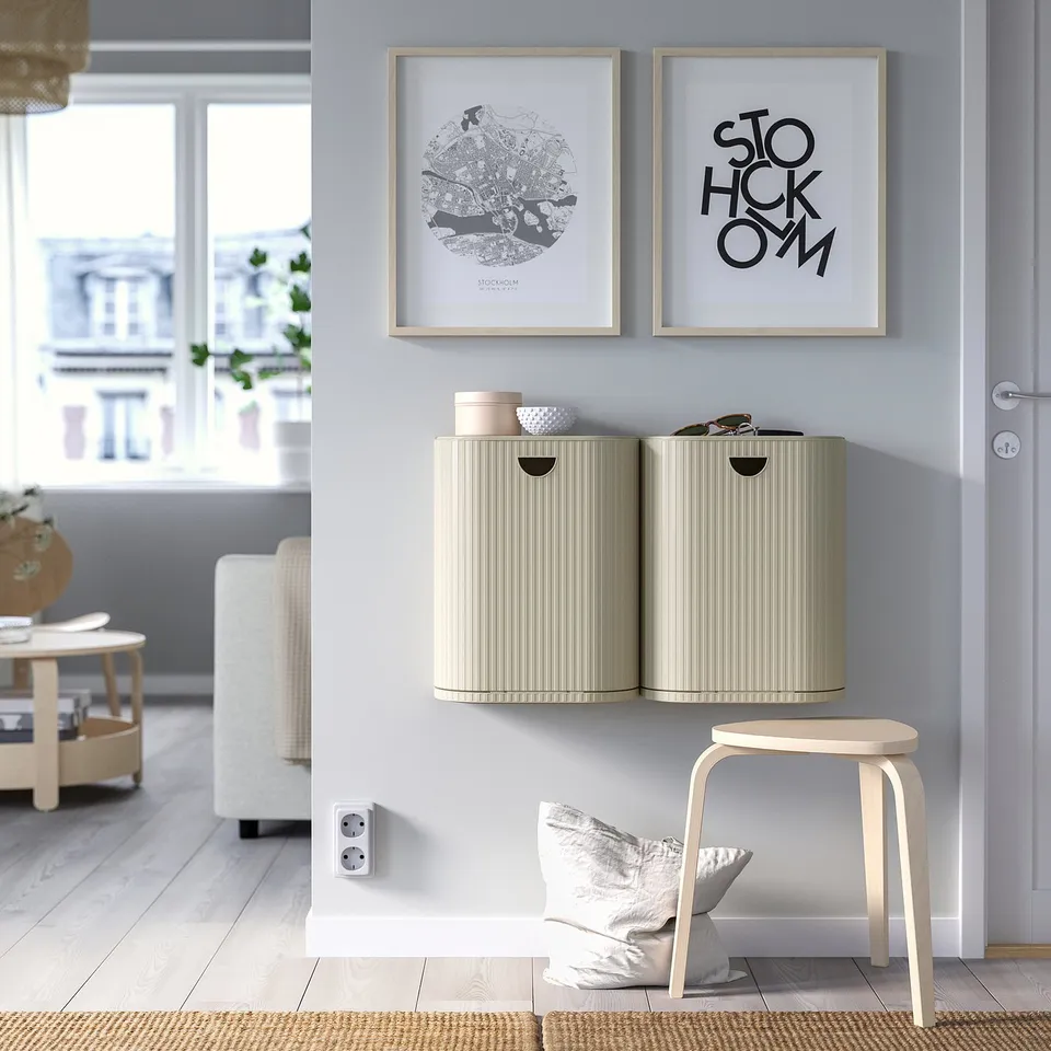 Two beige GÅRDSBUTIK bins on blue wall, under art. Compact, corrugated design with stool & pillow.