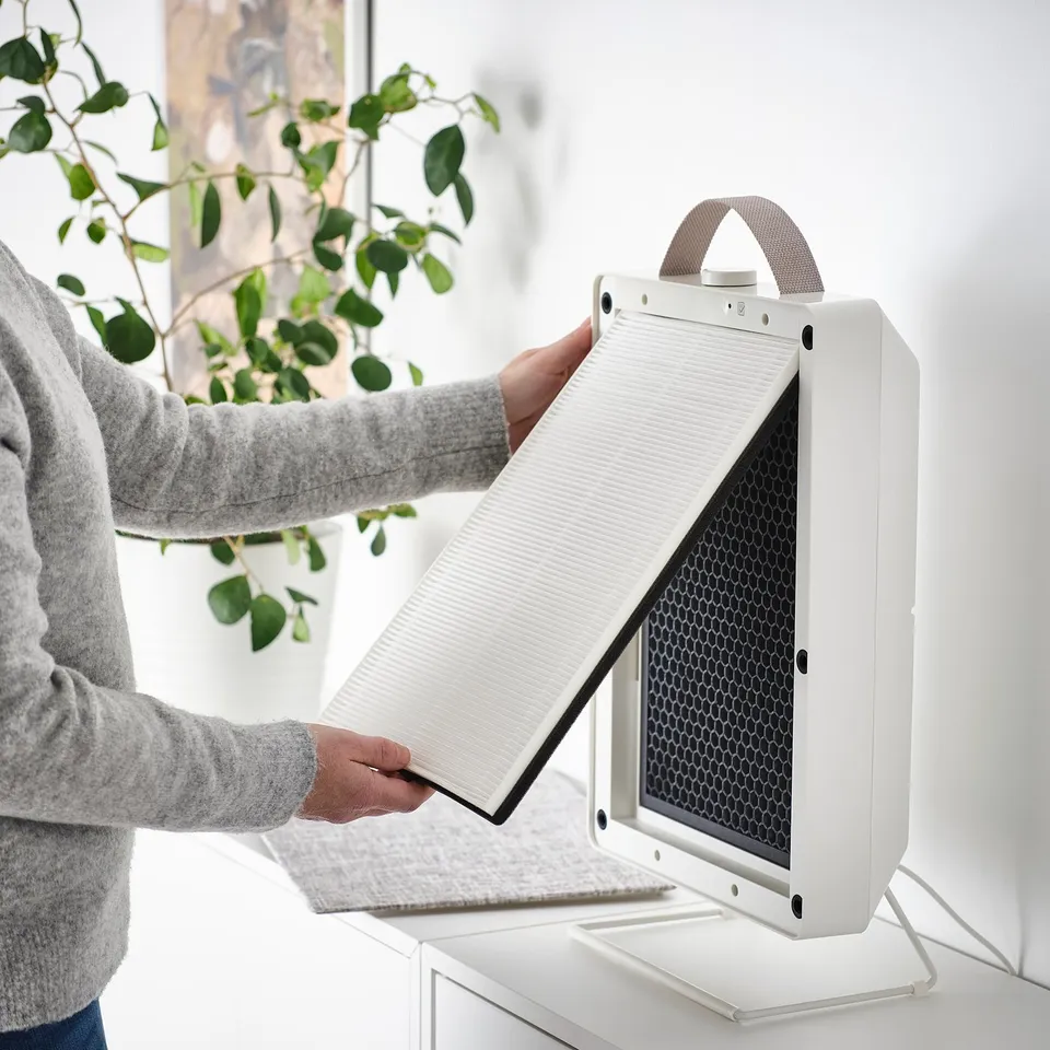 Inserting FÖRNUFTIG air philtre into white purifier for cleaner air.