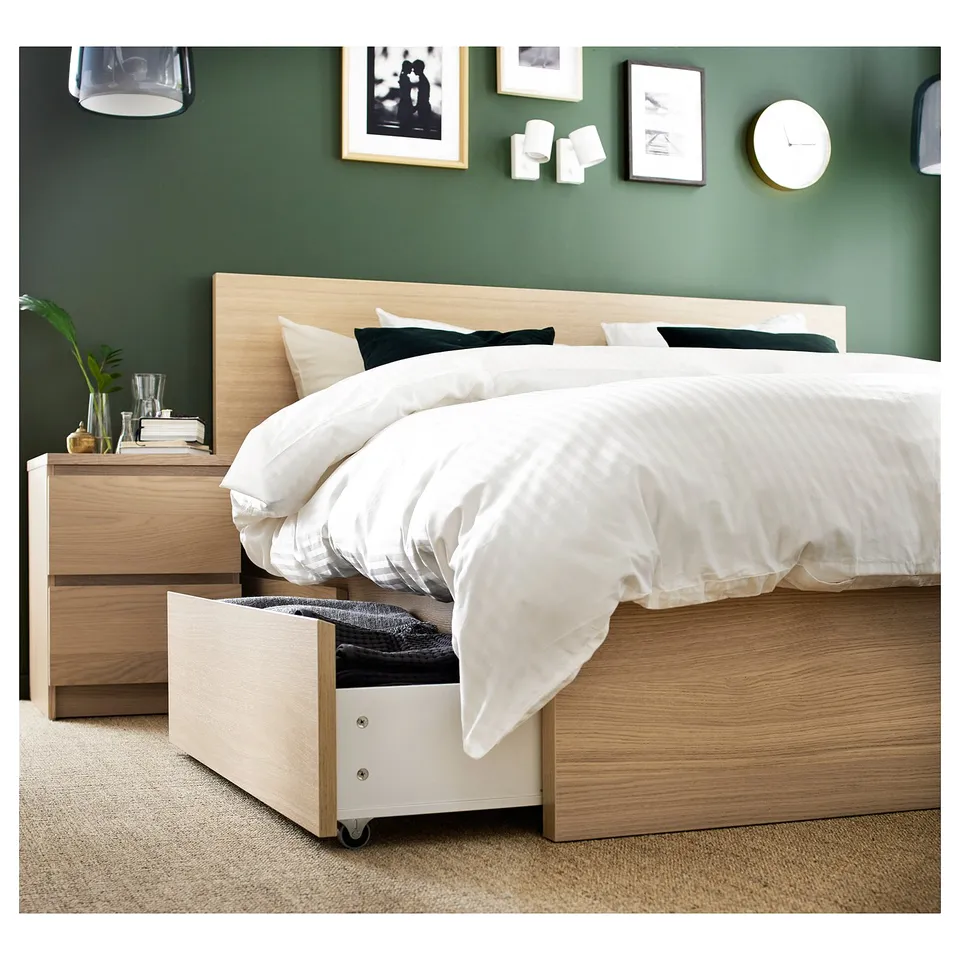 Modern bedroom with light wood MALM bed, white sheets, dark pillows, green wall, and wall art.