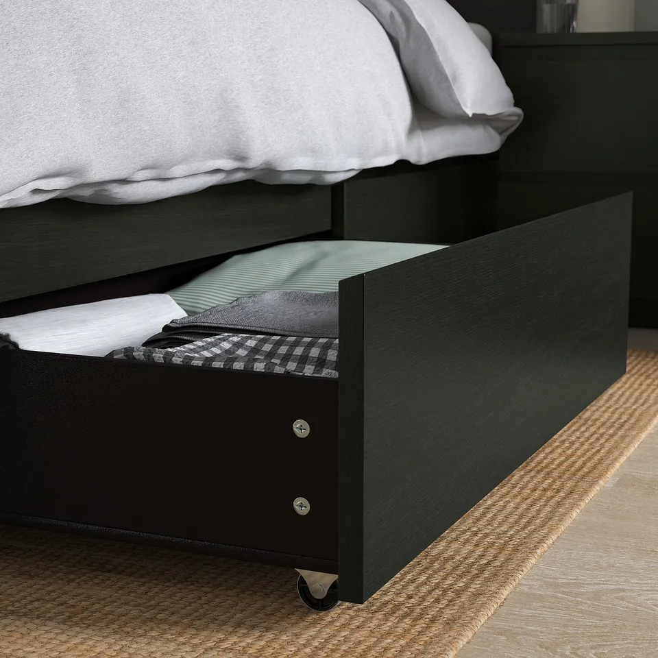 Black bed with open drawer showing folded blankets, demonstrating easy-access storage.