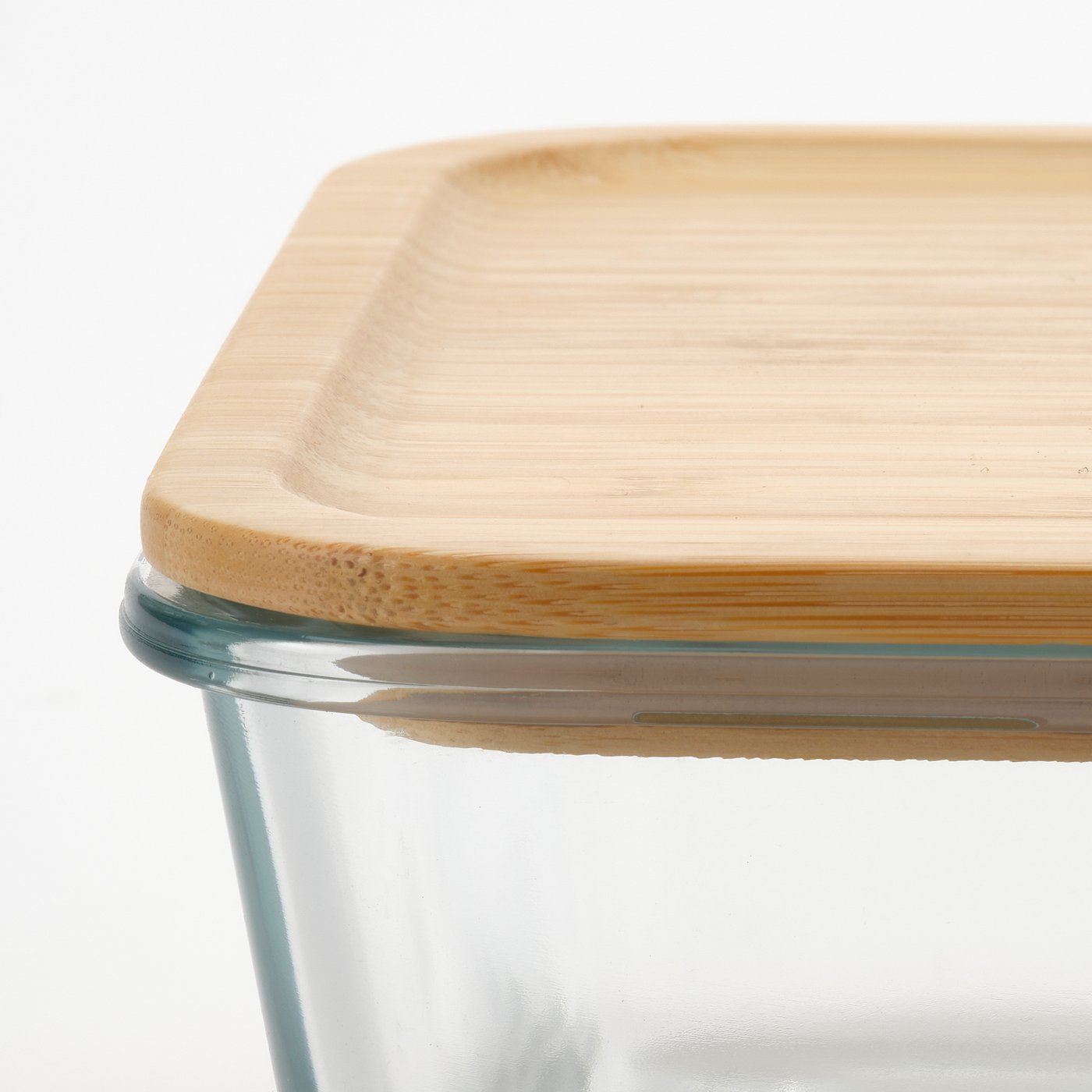 Close-up of a glass food container with a natural bamboo lid, showcasing its quality and materials.