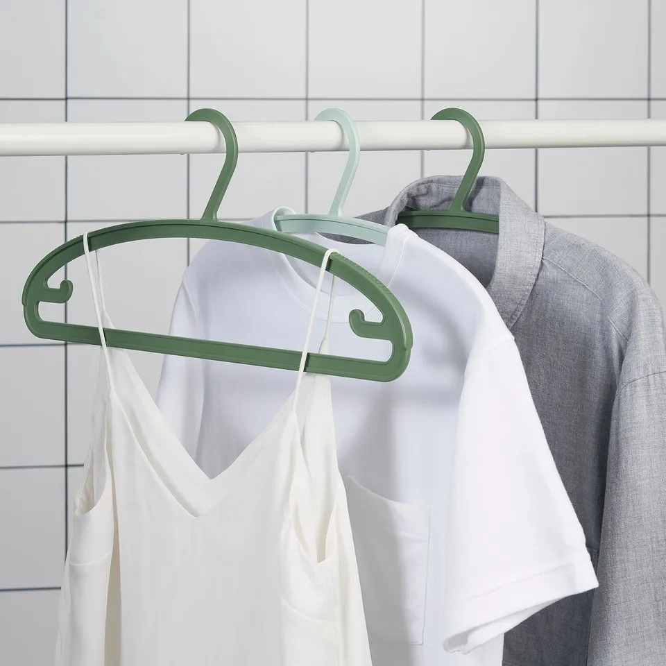 Clothes hangers with anti-slip shoulders in green, holding white and grey tops.