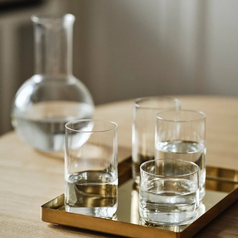 Modern glassware set with water, mouth-blown, on gold tray.