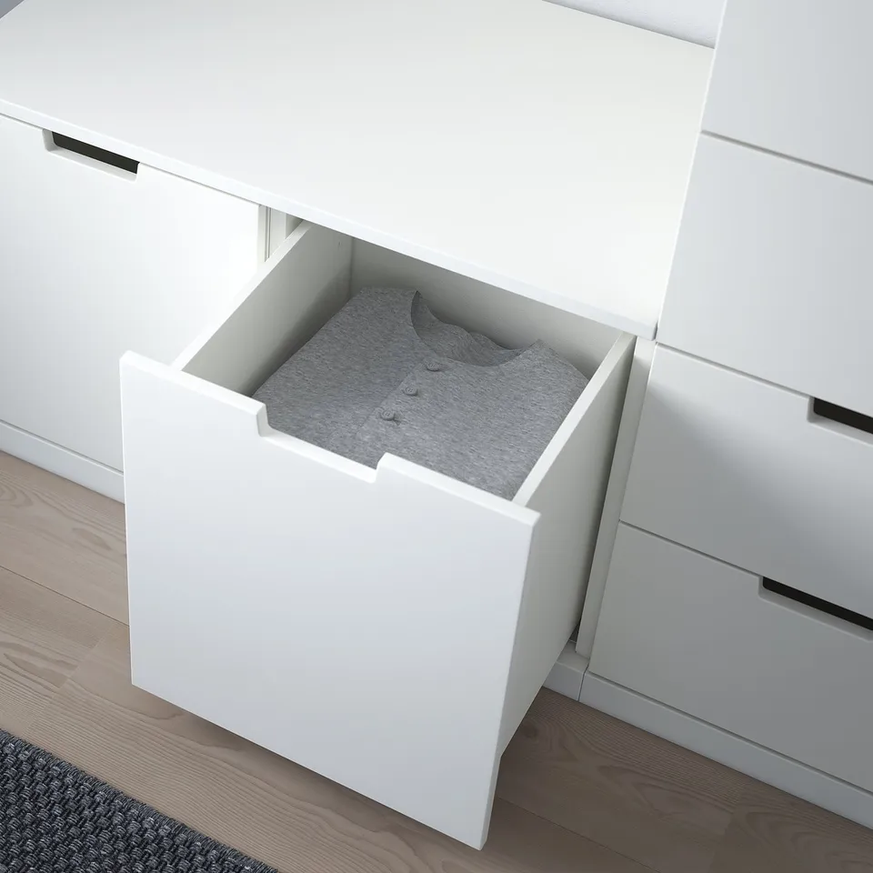 Open white NORDLI chest drawer revealing folded grey shirt, showcasing accessible and organised storage space.