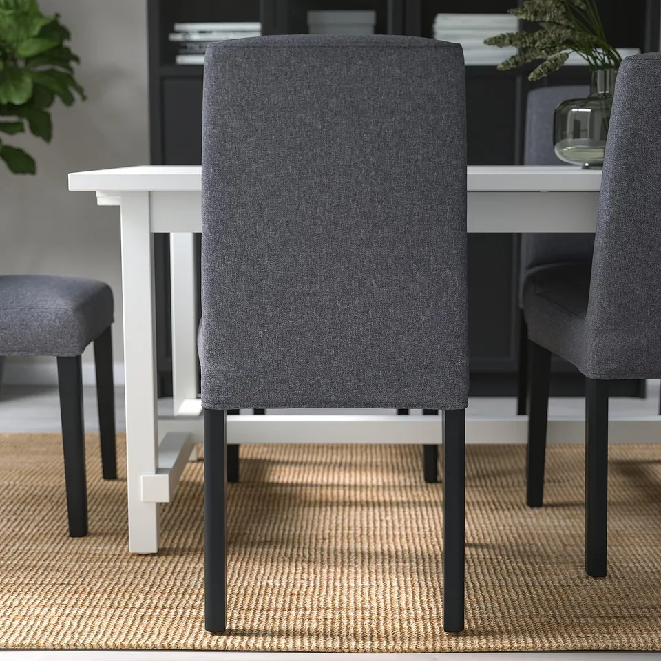 Modern grey fabric chairs with black legs around white table on rug.